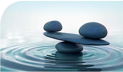 Bild vergrern: Zu sehen sind im Wasser aufgestapelte Steine, die eine ausgeglichene Waage symbolisieren.